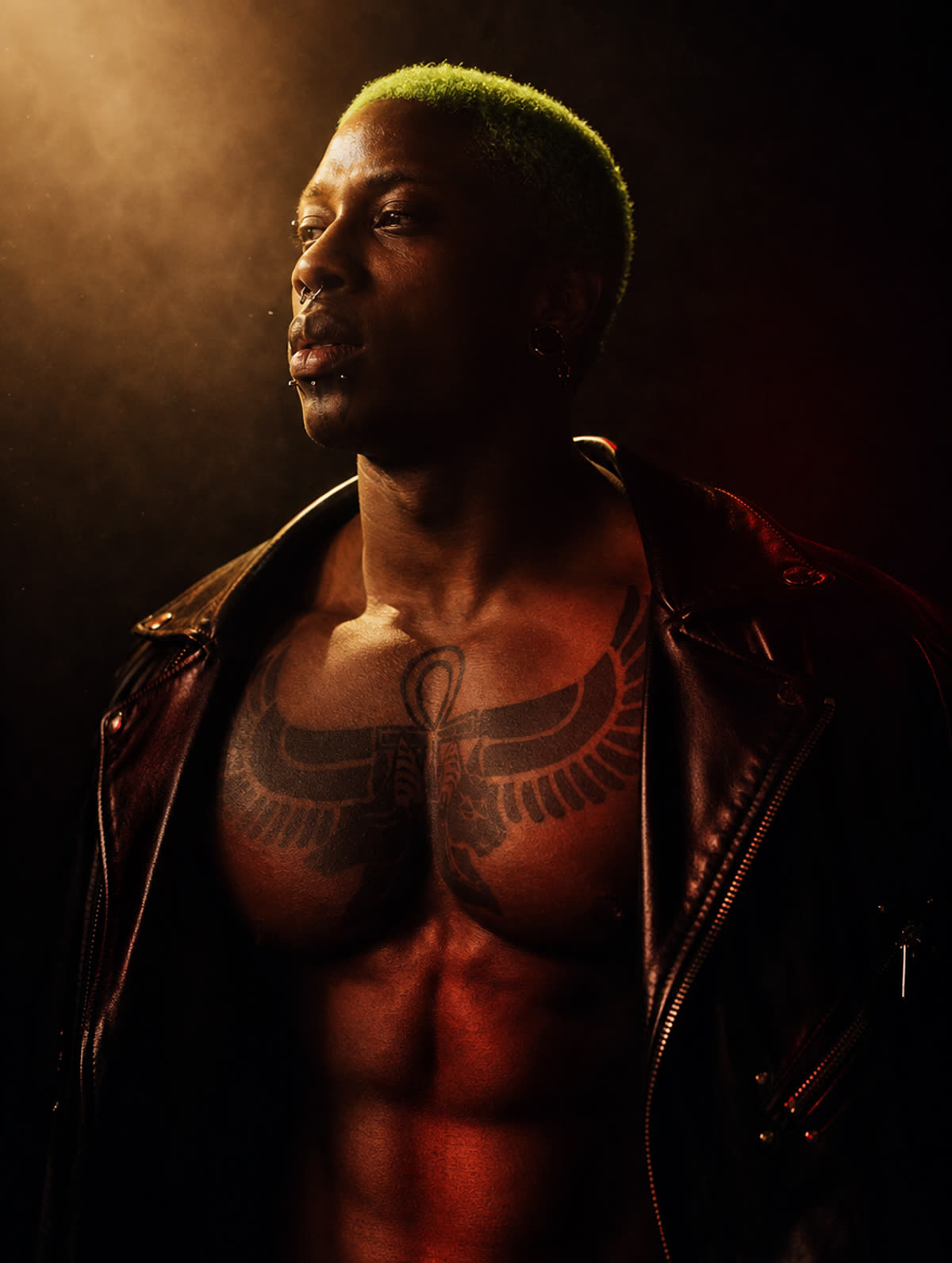 Steeve Aukingso en studio, veste de cuir ouverte sur son tatouage ailé