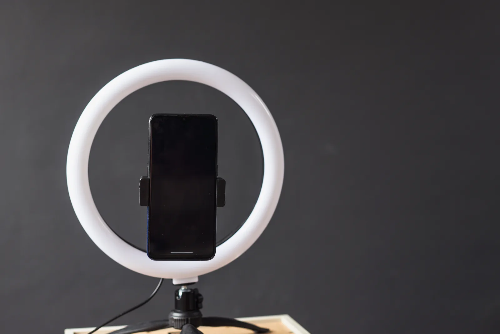 Un smartphone dans un anneau lumineux sur trépied, prêt à filmer